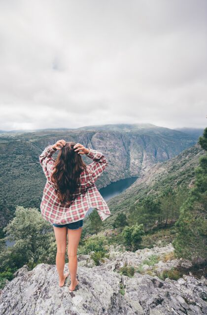 黑发西班牙西尔峡谷一名年轻白人妇女的垂直镜头悬崖金发年轻