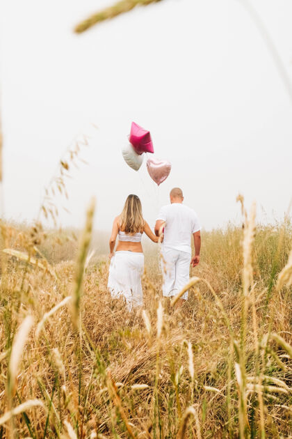 白种人一对高加索夫妇手持心形气球的垂直镜头微笑人心