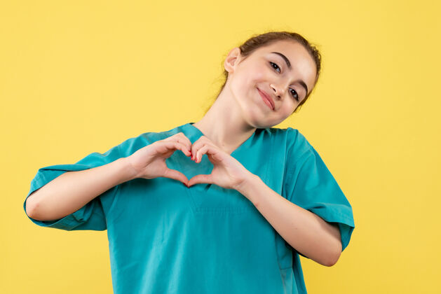 漂亮黄墙上年轻女医生身穿医疗衫送爱心的正面图护士肖像医疗