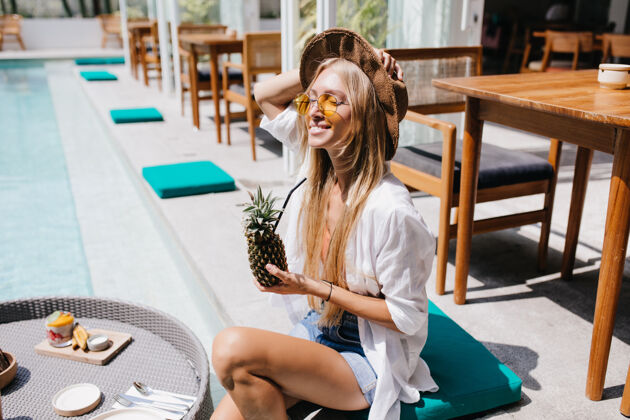 帽子美丽的年轻女子戴着太阳镜 在泳池边摆着菠萝造型迷人的长发女游客在度假胜地享用水果鸡尾酒女人阳光度假