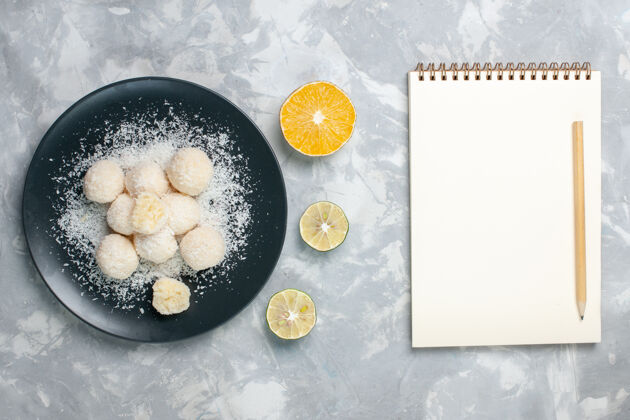 水果俯瞰椰子糖与记事本上的浅白色柠檬笔记本糖果