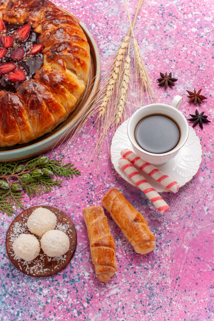 糖果俯瞰美味的草莓派 粉红色的桌子上放着一杯茶草莓茶饼干