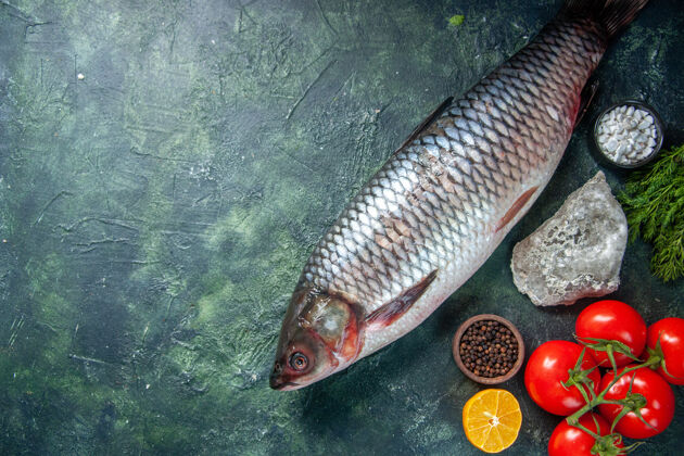 顶部顶视图新鲜生鱼与红色西红柿在黑暗的背景红色鱼鲈鱼