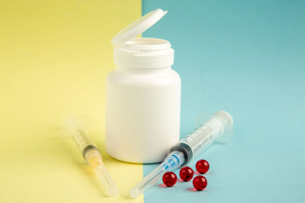 健康前视图白色塑料罐 带有注射剂和黄蓝色背景上的红色药丸视图瓶子病毒