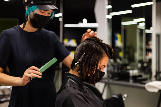 面膜一个专业的女理发师给客户理发这个女孩戴着面具坐在美容院里发廊时尚理发师