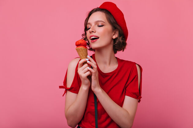 微笑穿着红衣服的漂亮年轻女子在吃冰淇淋优雅的法国女模特摆着甜点法国成人搞笑