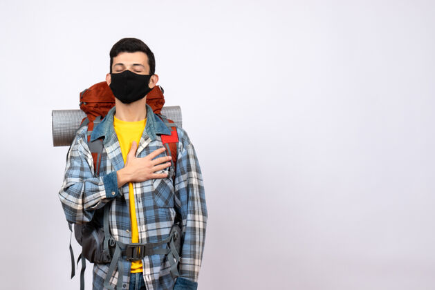 人正面图：背着背包 戴着面具的男性旅行者 手放在胸前 闭着眼睛视野封闭面具