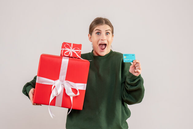 圣诞节前视图年轻女性带着圣诞礼物和银行卡节日人年轻女性