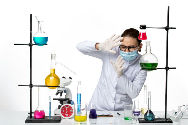 实验室前视图：穿着医疗服的女化学家戴着面罩在白色背景上工作病毒化学实验室covidsplash病毒实验室飞溅