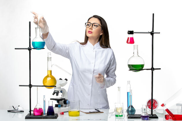 溶液前视图：穿着无菌医疗服的女化学家在白色背景实验室病毒冠状病毒上工作-大流行科学灭菌病毒烧杯