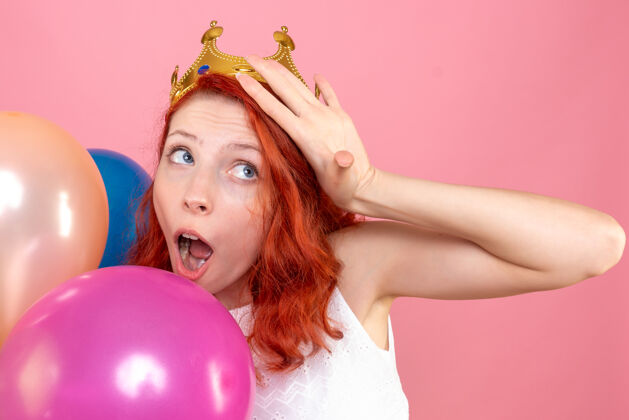 女人正面近距离观看手持粉色彩色气球的年轻女性肖像运动气球