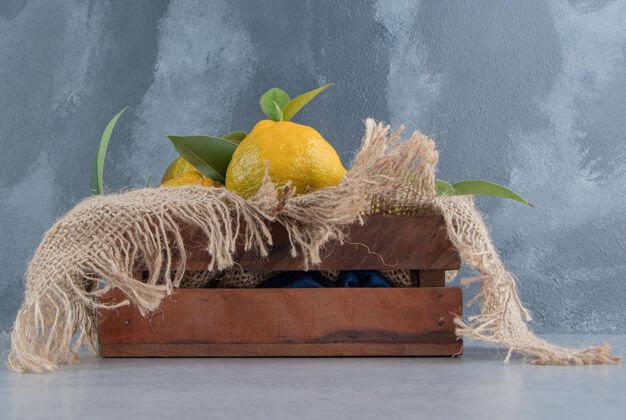 柳条箱用一块布盖着的木箱 大理石上装满了橘子配料美味水果