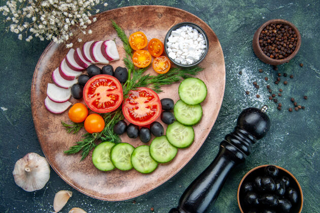 蔬菜顶视图新鲜切碎的蔬菜橄榄盐在一个棕色的盘子和厨房锤子大蒜素花绿黑色混合色背景厨房切碎的蔬菜花