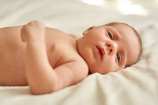 新生儿可爱的新生婴儿躺在床上的白色毯子上 研究着外面的事物 可爱可爱的婴儿 美丽的孩子看着远处华丽睡眠无辜