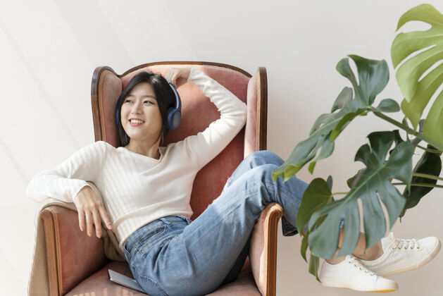 乐趣在红色沙发上听音乐的亚洲女人娱乐叶室内