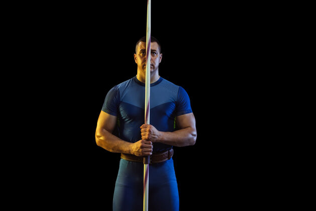 运动男运动员在霓虹灯下练习在黑色背景上投掷标枪职业运动员摆出自信的姿势健康的生活方式 运动 活动 比赛的概念复制空间冠军强壮能量