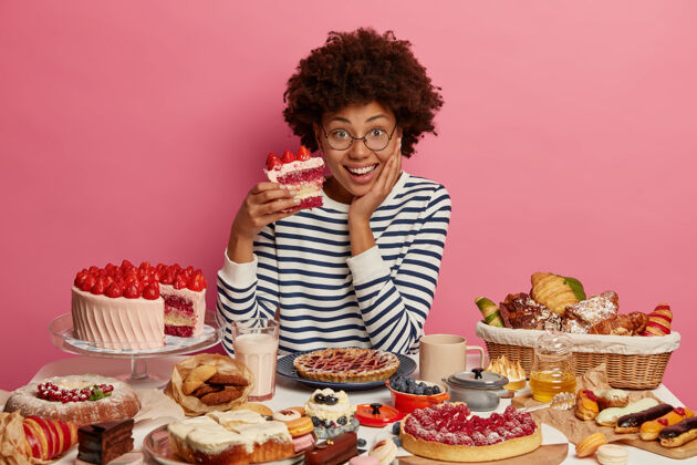 女性积极的女人爱吃甜食 品尝美味的草莓蛋糕 打破饮食习惯 吃高热量的食物 坐在大桌子上吃糖果非洲蛋糕味道