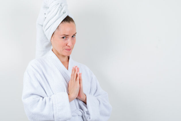 人年轻的女士手牵手在祈祷的姿态在白色浴衣 毛巾和期待 正面视图浴袍女士新鲜