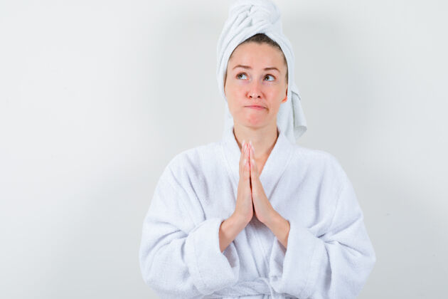 人身穿白色浴袍的年轻女士 手拿毛巾做祈祷的姿势 看上去充满希望 正前方的景色女人水疗健康