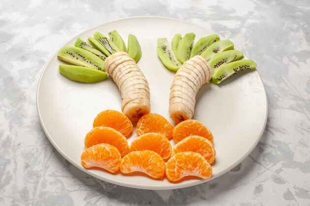 生的正面视图切片水果猕猴桃香蕉和橘子白色表面水果异国情调热带新鲜醇香醇香午餐热带