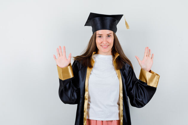 学术女毕业生的肖像展示在制服 休闲服投降手势手掌 看起来自信的正面视图成就前线投降