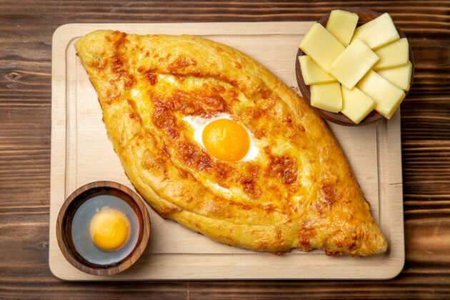 面团顶视图棕色木地板上新鲜烤面包和熟鸡蛋面团餐包早餐鸡蛋食品烹饪奶酪鸡蛋