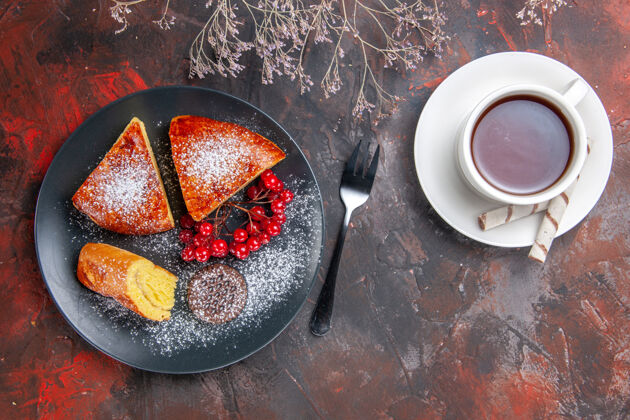 浆果俯瞰美味的切片馅饼与红色浆果在黑暗的桌子蛋糕甜甜的馅饼茶杯子深色容器
