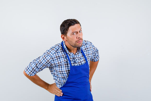 烹饪穿着蓝色围裙和衬衫的年轻男厨师厨师制服衬衫