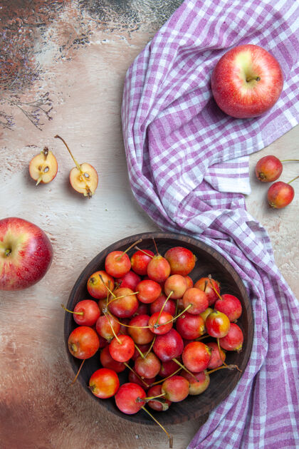 顶部樱桃俯视图两个苹果樱桃在碗里的格子桌布上成熟油桃樱桃