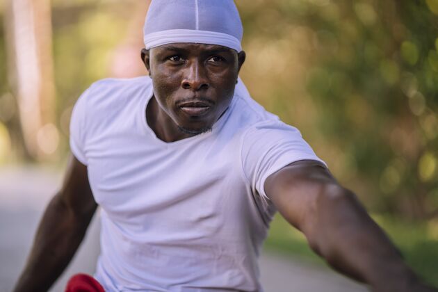 形状一个穿着白衬衫的非洲裔美国男性在公园伸展的特写镜头教练运动装休闲