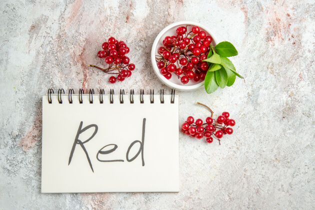 写作顶视图红色小红莓与红色书写记事本在白色桌子上新鲜的浆果红色水果健康草莓饮食