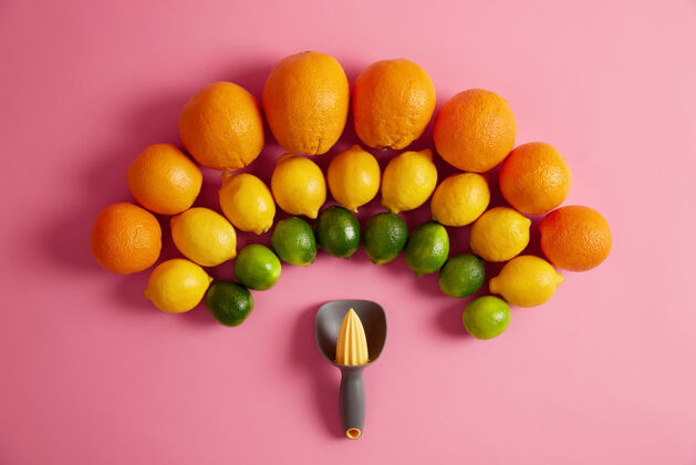 橙子新鲜的橙子 黄色的柠檬和绿色的酸橙排列在半圆形的手动榨汁机上方榨汁机用于从柑橘类水果中制备有机果汁维生素和健康的生活方式理念风味酸橙素食