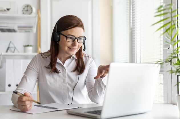 办公桌工作中的肖像女性在笔记本电脑上进行视频通话耳机女性工作