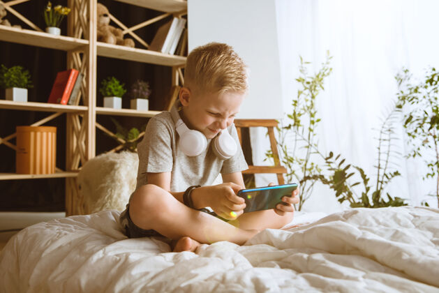 上瘾男孩在家里使用不同的小玩意小模型智能手表 智能手机或平板电脑和耳机信息青少年房间