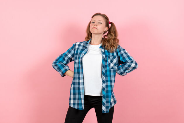 年轻正面图身着蓝色格子衬衫的年轻女性在粉色背景上摆姿势青春情感女孩儿童模特时尚成人女孩衬衫