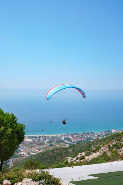 风险橙色的滑翔伞在阳光明媚的夏日飞越山谷自由飞行活动