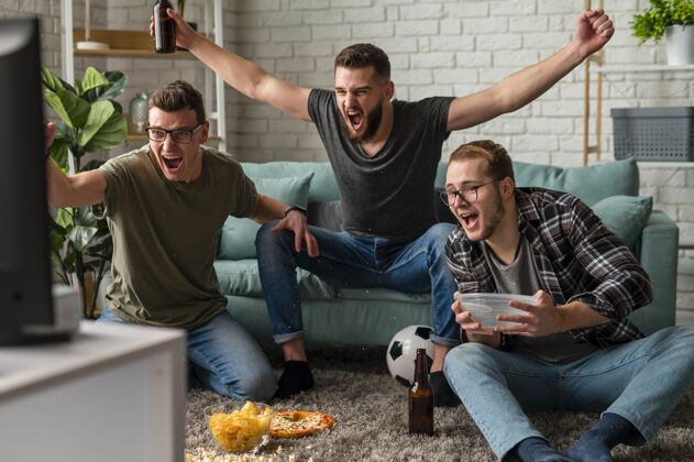 最好的朋友快乐的男性朋友一起看电视体育节目 一边吃零食和啤酒电视啤酒瓶同志