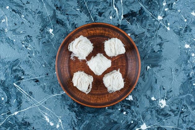 土耳其语传统的土耳其棉花糖放在木制盘子上 蓝色背景糖美味美味