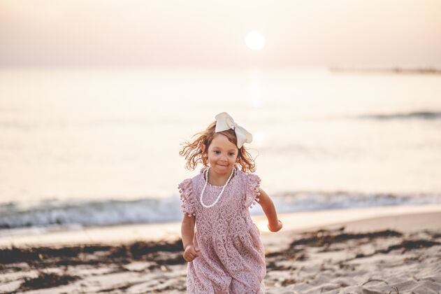 白种人海滩上一个金发小女孩的浅焦镜头小跑步浅