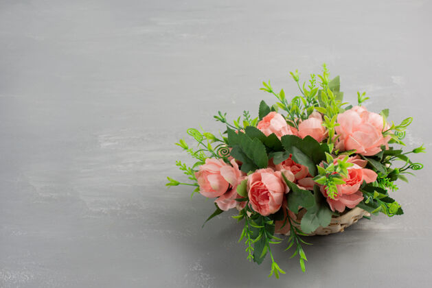 花束在灰色的桌子上放着一束美丽的粉红玫瑰婚礼安排叶子