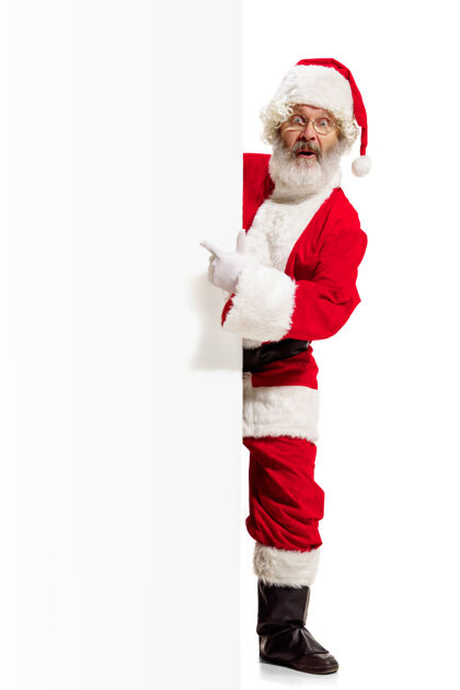 季节快乐惊喜的圣诞老人指着空白广告墙上的复制空间主题广告牌人