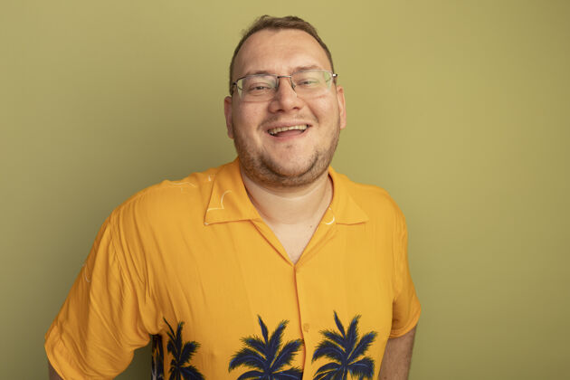 微笑戴着眼镜的男人穿着橘色衬衫 脸上带着灿烂的笑容站在绿色的墙上欢呼戴眼镜