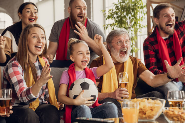 家庭兴奋 快乐的大家庭在家里的沙发上看足球 足球比赛球迷们为最喜爱的国家队欢呼从爷爷奶奶到孩子们玩得开心体育 电视 冠军观看电视肖像