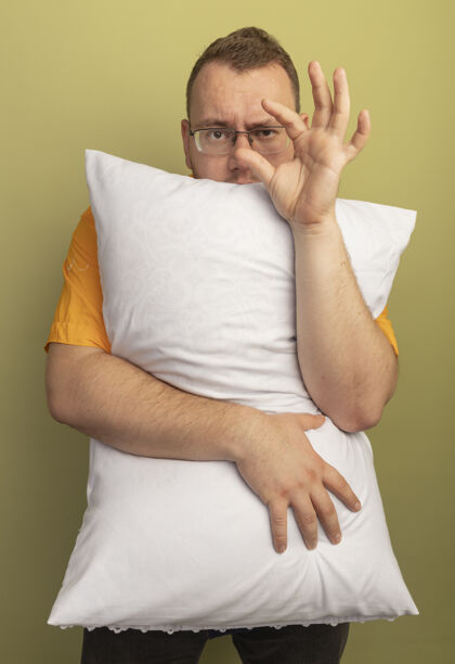 测量戴着眼镜的男人穿着橘色衬衫抱枕 展示小尺寸的手势 象征着站在光墙上的测量手势显示枕头