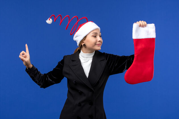 人正面图：年轻女性手持红色圣诞袜站在蓝色办公桌上过年前面观点年轻女性