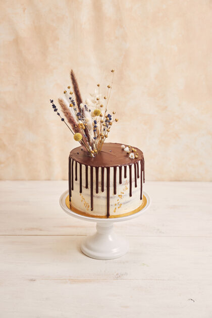 餐厅垂直拍摄美味波西米亚蛋糕与巧克力滴和鲜花上的黄金装饰美味盘子糕点