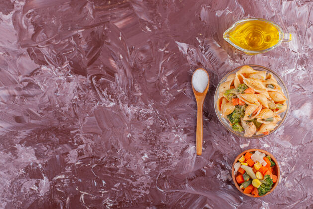 餐意大利贝壳面食 油和混合蔬菜沙拉 放在浅色桌上酱汁面食有机