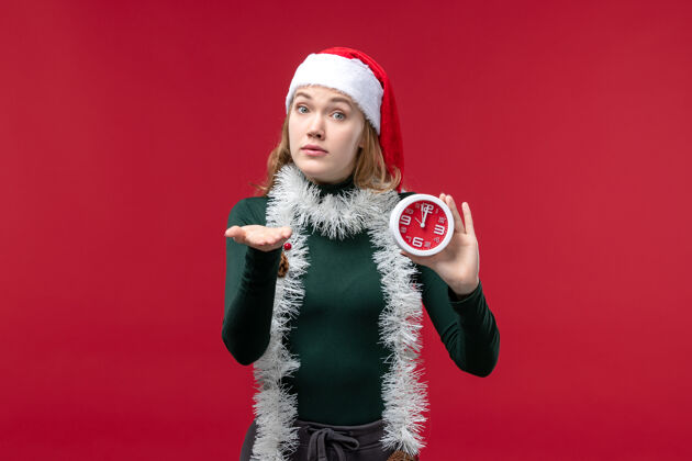 视图正面图年轻的女性拿着红色地板上的时钟新年圣诞红色假期人圣诞节时钟