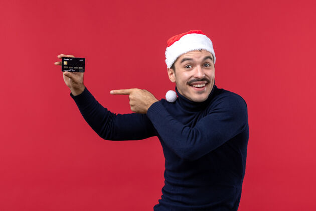 男人正面图年轻男子手持红色背景的黑色银行卡银行圣诞卡片