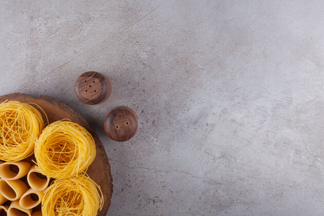 饮食意大利通心粉和生的管状通心粉在木片上做成的小窝菜面食团体